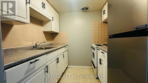 A kitchen with white cabinets and a black refrigerator.