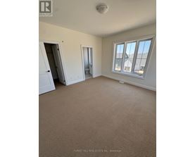 A room with a carpeted floor and a window overlooking a building.