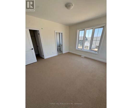 A room with a carpeted floor and a window overlooking a building.