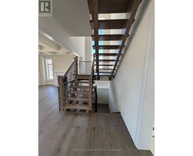 A wooden staircase with a metal railing in a white room.