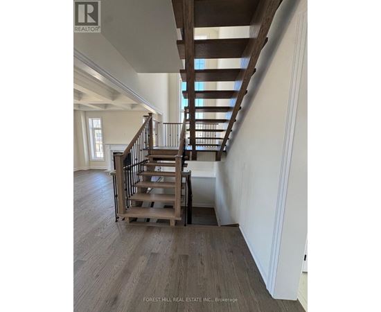 A wooden staircase with a metal railing in a white room.