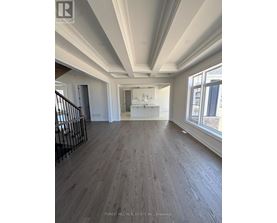 A spacious room with wood flooring and a staircase with metal railings.