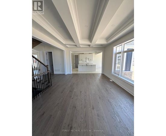 A spacious room with wood flooring and a staircase with metal railings.
