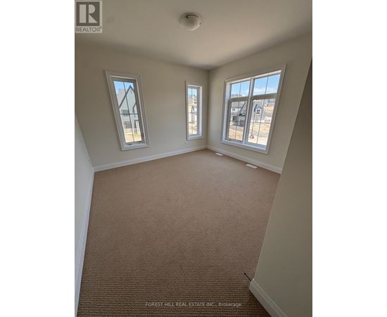 A room with carpet flooring and two windows.