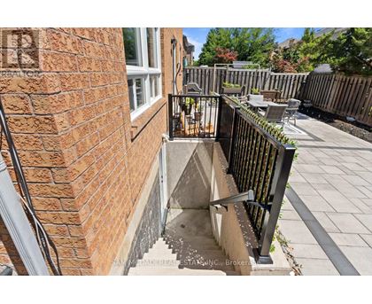 A brick wall with a black railing and a small concrete staircase.