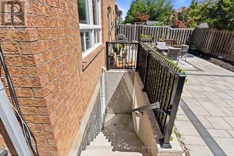A brick wall with a black railing and a small concrete staircase.