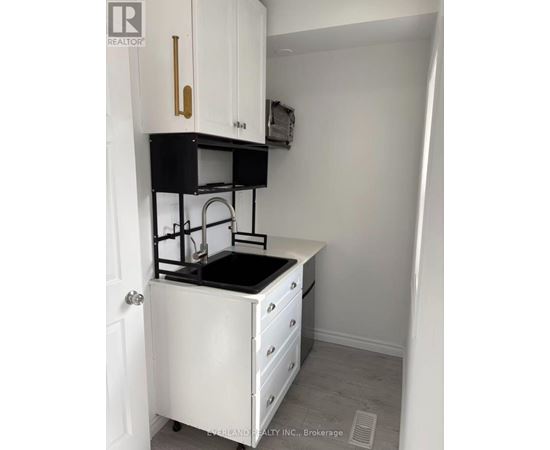 A small white kitchen with a black counter top.