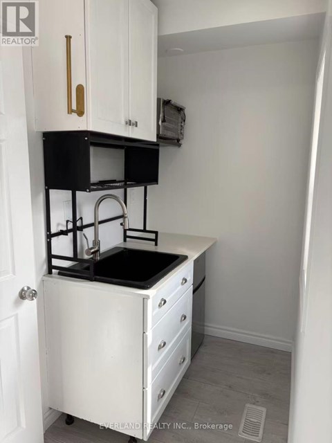 A small white kitchen with a black counter top.