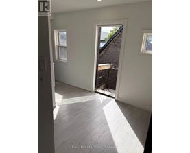 A room with white walls and a window overlooking a backyard.