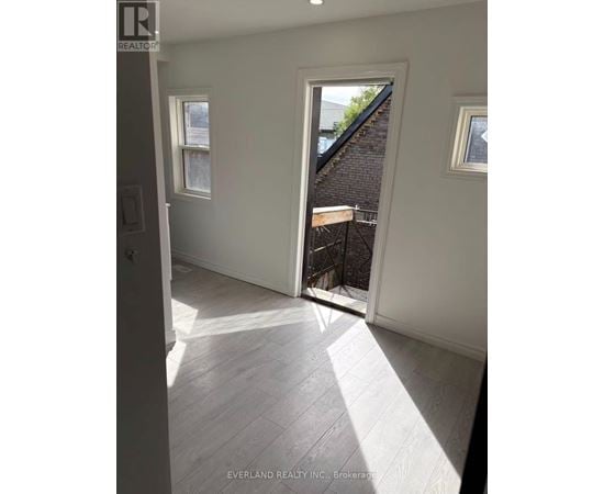 A room with white walls and a window overlooking a backyard.