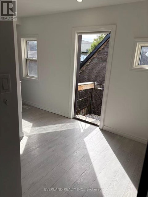 A room with white walls and a window overlooking a backyard.