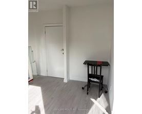 A room with a white door and a black table with wheels.