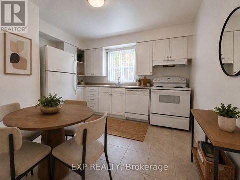 A kitchen with white appliances and a round table with chairs.