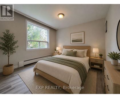 A bedroom with a bed, nightstand, and a plant.