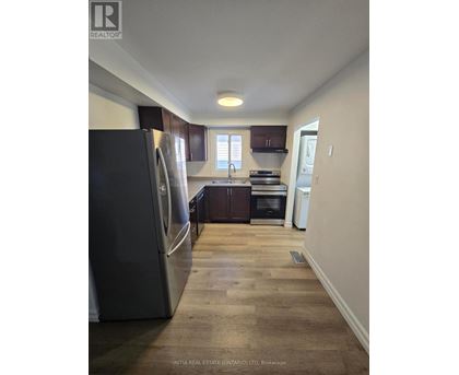 A kitchen with a refrigerator, oven, and sink.