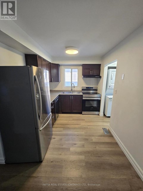 A kitchen with a refrigerator, oven, and sink.