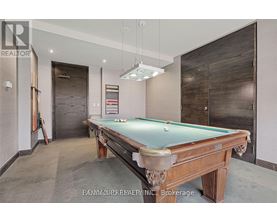 A pool table in a room with a realtor sign.