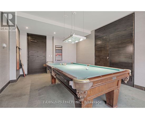 A pool table in a room with a realtor sign.