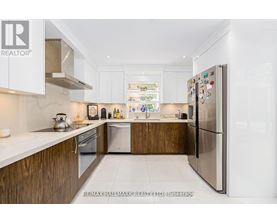 A modern kitchen with white cabinets and a refrigerator.