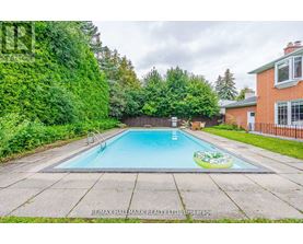 A small pool in a backyard surrounded by a fence and trees.