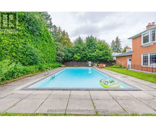 A small pool in a backyard surrounded by a fence and trees.