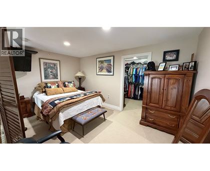 A bedroom with a bed, a chair, and a wardrobe.