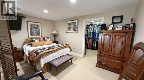 A bedroom with a bed, a chair, and a wardrobe.