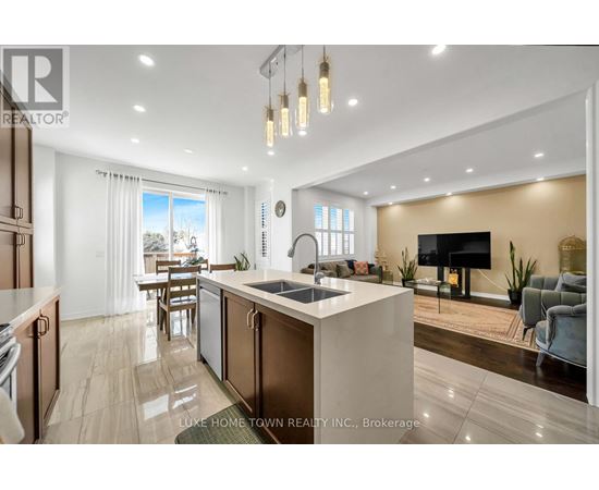 A modern kitchen with a large island and a living area with a couch and a TV.