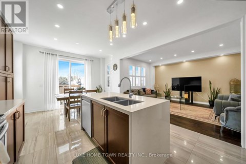 A modern kitchen with a large island and a living area with a couch and a TV.