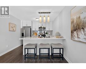 A kitchen with white cabinets and a white island with bar stools.