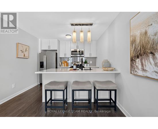 A kitchen with white cabinets and a white island with bar stools.