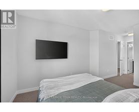 A bedroom with a bed and a flat screen TV mounted on the wall.