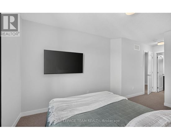 A bedroom with a bed and a flat screen TV mounted on the wall.