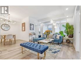 A living room with a blue ottoman and a white chair.