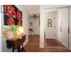 A hallway with a flower arrangement on a table and a fan on the wall.