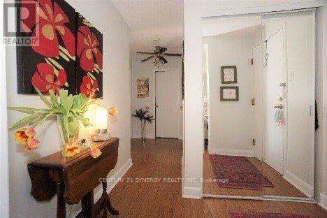 A hallway with a flower arrangement on a table and a fan on the wall.