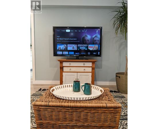 A television is on in a living room with a tray on a wicker basket in front of it.