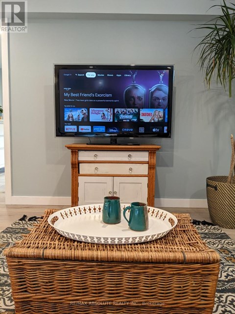 A television is on in a living room with a tray on a wicker basket in front of it.