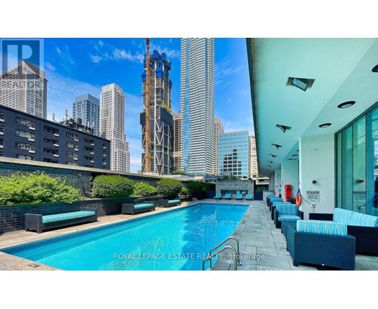 A swimming pool is surrounded by lounge chairs on the roof of a building.