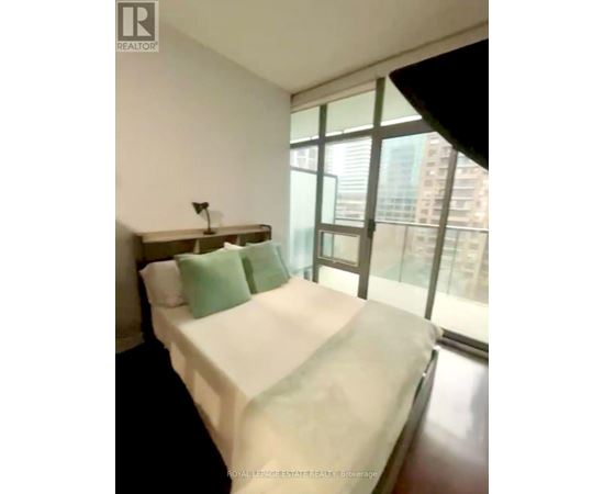 A bedroom with a large bed and a window overlooking a city.