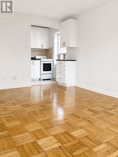 A kitchen with white cabinets and a wooden floor.