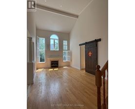 A spacious room with a fireplace and wooden flooring.