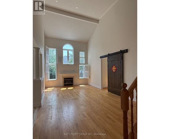 A spacious room with a fireplace and wooden flooring.