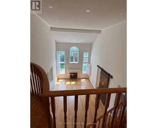 A view from the top of a staircase looking down at a living room with a fireplace and a bay window.