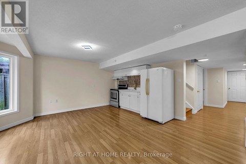 A kitchen area with white appliances and wooden flooring.