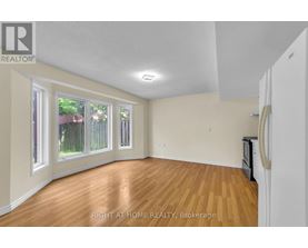 A room with wooden floors and white walls, with a window showing a fence and trees outside.
