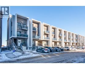 A row of modern apartment buildings with cars parked in front.