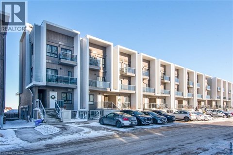 A row of modern apartment buildings with cars parked in front.