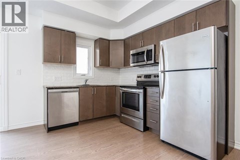 A kitchen with a refrigerator, microwave, oven, and dishwasher.