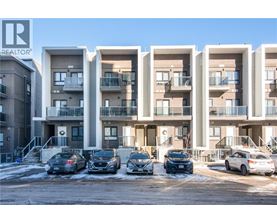 A row of modern apartment buildings with cars parked in front.